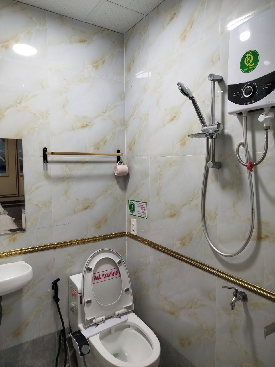 Un baño con inodoro, lavamanos, ducha y perchero para toallas.