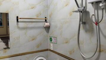 Un baño con inodoro, lavamanos, ducha y perchero para toallas.