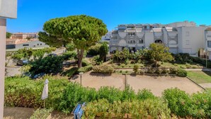 Edifício residencial com várias varandas e um jardim com diversas plantas e uma grande árvore.