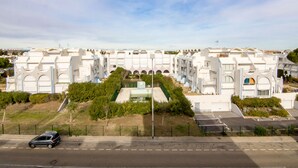 Um complexo hoteleiro moderno com vários edifícios brancos, um pátio central e estacionamento.