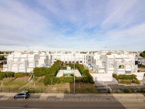 Ein moderner Hotelkomplex mit mehreren weißen Gebäuden, einem Innenhof und einem Parkplatz.