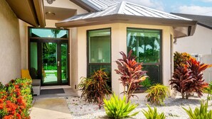 Un bâtiment moderne doté d’une grande entrée en verre, d’un porche abrité et d’un jardin bien entretenu où poussent différentes espèces de plantes.