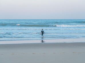 A beach scene with a person walking towards the water, carrying a surfboard. - Les Sentes by Interhome (Maubuisson)