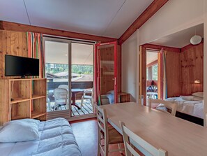 A cozy room with a bed, a dining table, and a TV mounted on the wall.