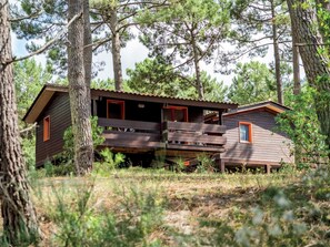 A cabin with a wooden exterior, a balcony, and a red door.