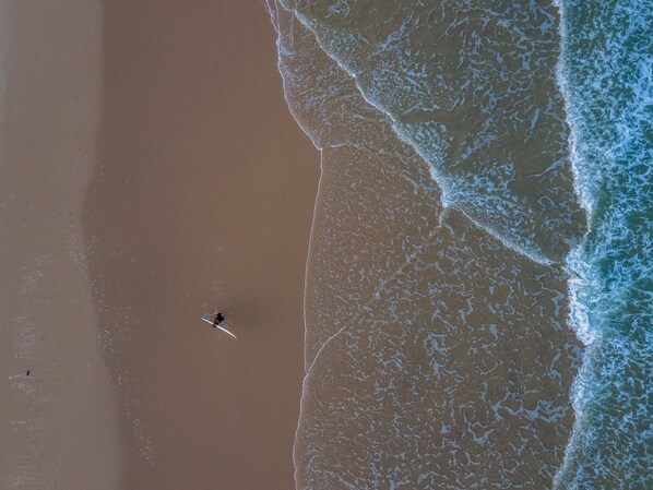 A beach with a person paddling a kayak.