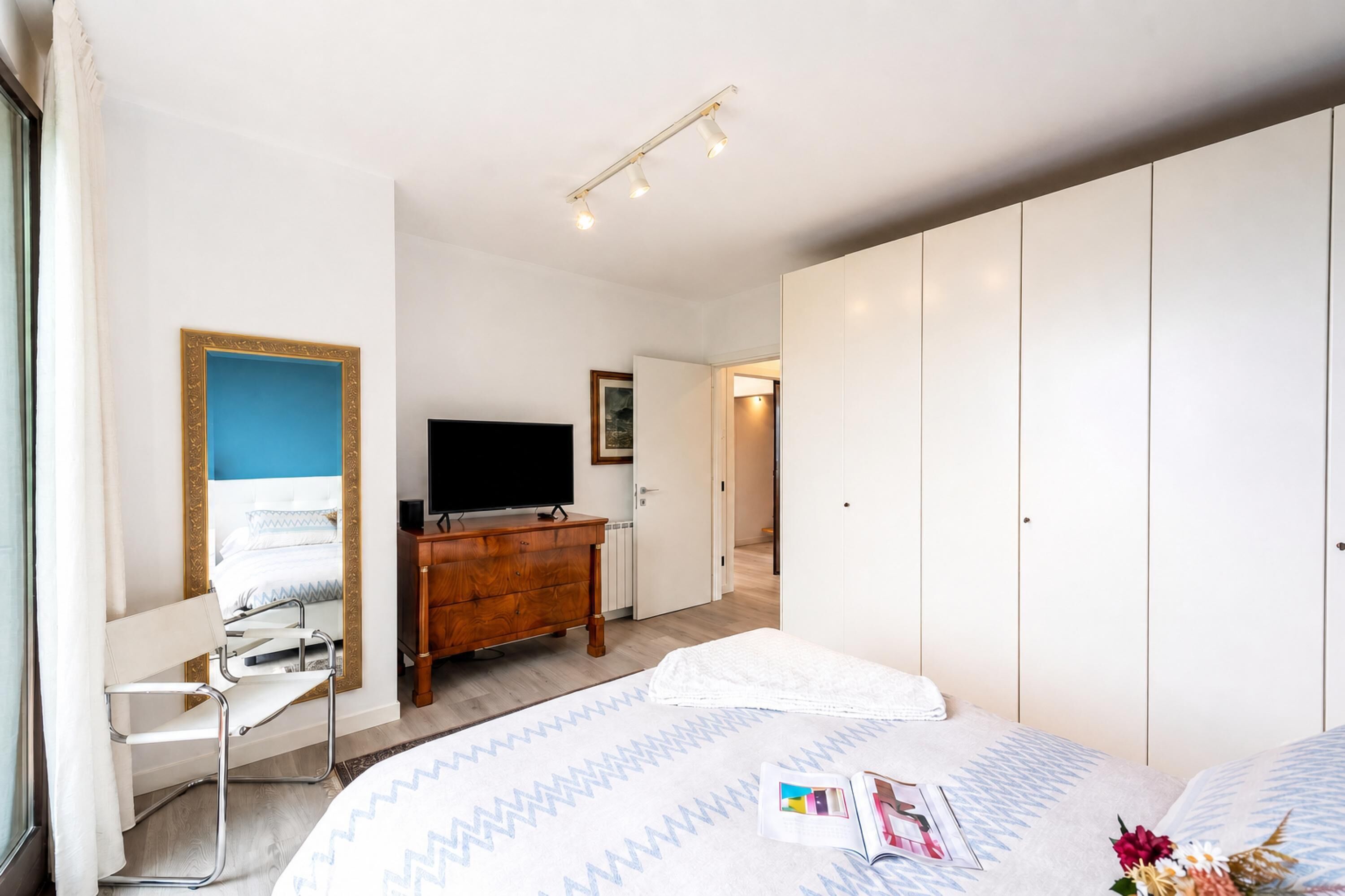 Ein Hotelzimmer mit Bett, Kommode, Fernseher und Kleiderschrank.