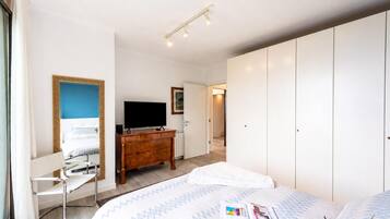 Ein Hotelzimmer mit Bett, Kommode, Fernseher und Kleiderschrank.