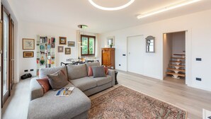 Een moderne woonkamer met een grijze modulaire bank, een kamerkleed en een trap naar een ander niveau.