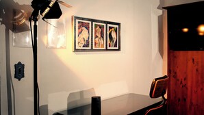 A room with a table, a chair, a lamp, and three framed artworks on the wall. - Urbanature Filme Arte Paulista Sp (São Paulo)
