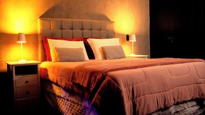 A bedroom with a tufted headboard, a large bed with multiple pillows, and bedside lamps on nightstands. - Urbanature Filme Arte Paulista Sp (São Paulo)