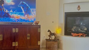 Ein Wohnzimmer mit Fernseher, Kamin und einer dekorativen Pferdefigur.