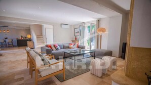A spacious living room with a grey sofa, a coffee table, and a dining area in the background. - GASSIN BEAUTIFUL VILLA WITH SWIMMING POOL (GASSIN)