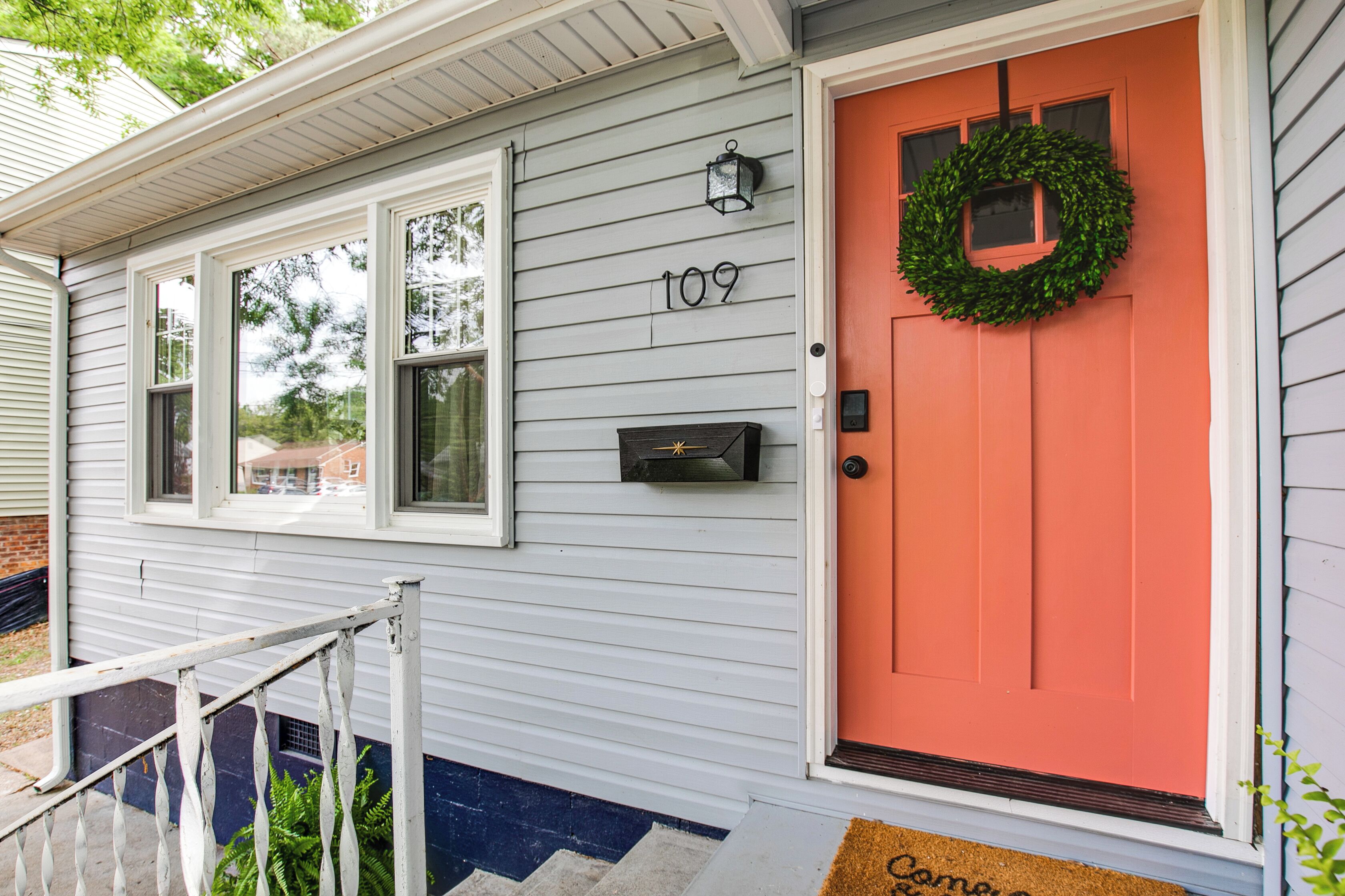A house with a number 109 on the wall, a red door, and a green wreath.