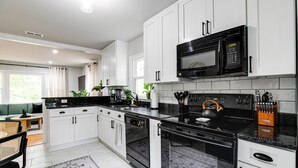 A modern kitchen with white cabinets, black appliances, and a black countertop.