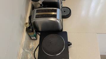 Una cocina con un tostador, una tetera y dos teteras eléctricas sobre la encimera.