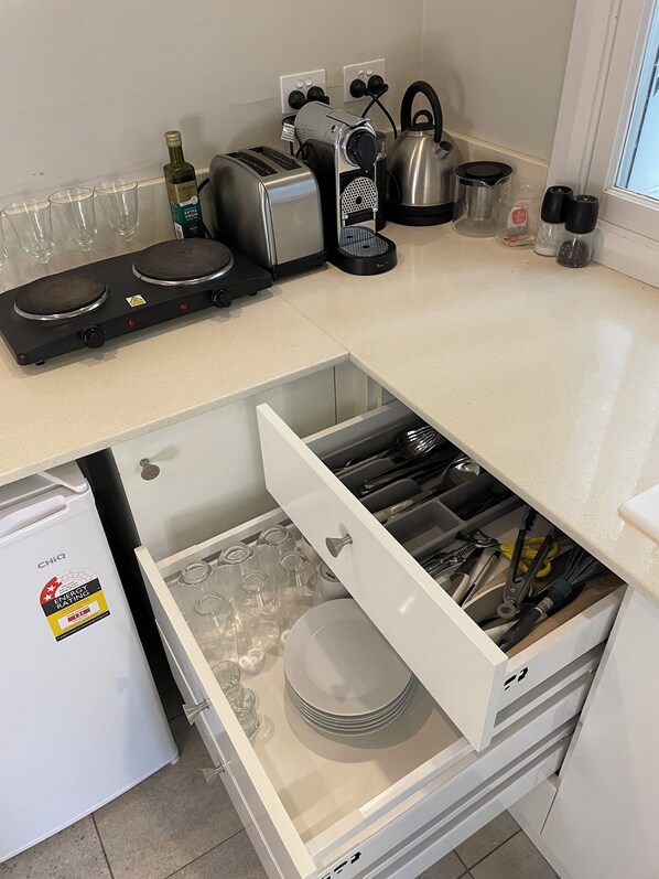 Una cocina con lavavajillas integrado, tostadora, hervidor y una botella de vino.