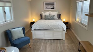 Une chambre à coucher avec un lit, des lampes de chevet, une chaise et un tableau au mur.