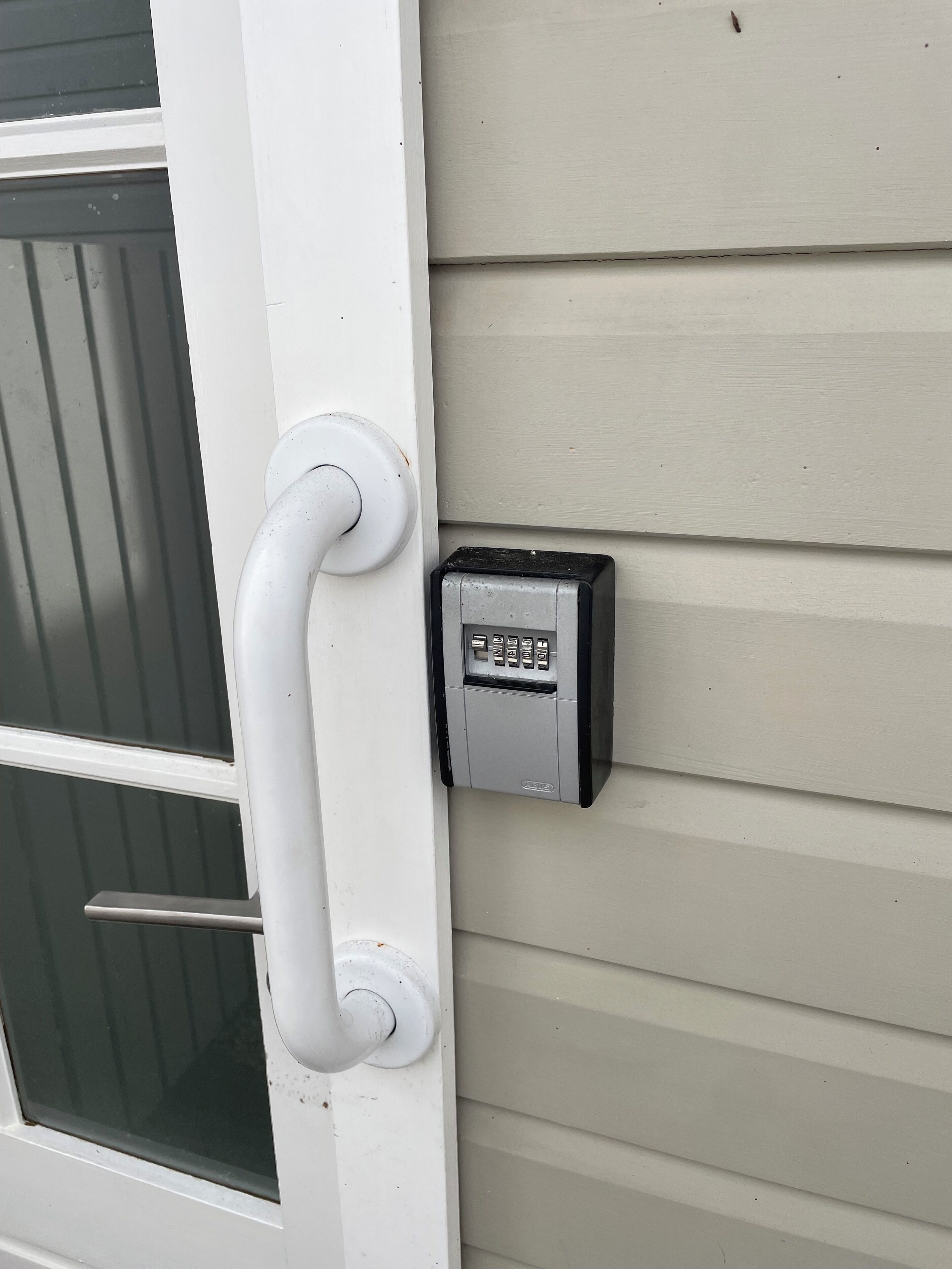 A door with a white handle and a keypad lock on the wall beside it.