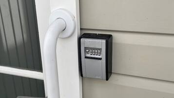 A door with a white handle and a keypad lock on the wall beside it.