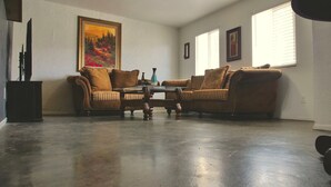 Ein Wohnzimmer mit zwei braunen Sofas, einem Glastisch und einem Bild an der Wand.