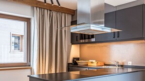Une cuisine moderne dotée d’un îlot central, d’appareils électroménagers en acier inoxydable et d’une fenêtre agrémentée de rideaux.