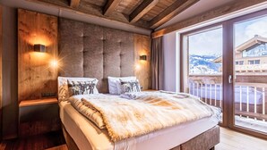 Une chambre avec un grand lit, une tête de lit en bois et deux lampes fixées au mur.