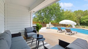 En overdækket patio med pool, liggestole og et bord med en plante.