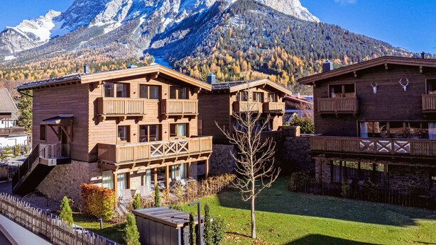 Un chalet en bois doté de balcons, d’une façade en pierre et offrant une vue sur des montagnes enneigées.