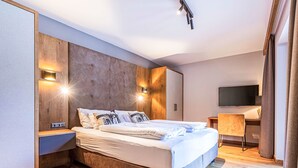 Une chambre d’hôtel moderne dotée d’un grand lit, d’une tête de lit en bois, de lampes de chevet, d’un bureau et d’un téléviseur à écran plat.