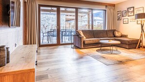 Un salon moderne avec un plancher en bois, un canapé, une table basse et un téléviseur fixé au mur.