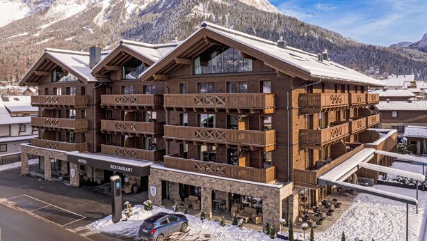 A multi-story wooden building with balconies, a restaurant, and a hotel sign.