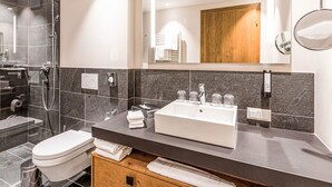 A modern bathroom with a glass-enclosed shower, a white sink with a vanity, and a wooden cabinet below.
