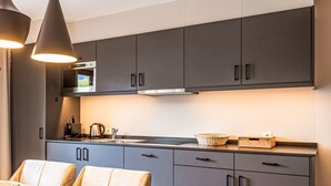 A modern kitchen with grey cabinets, a wooden dining table, and pendant lighting.