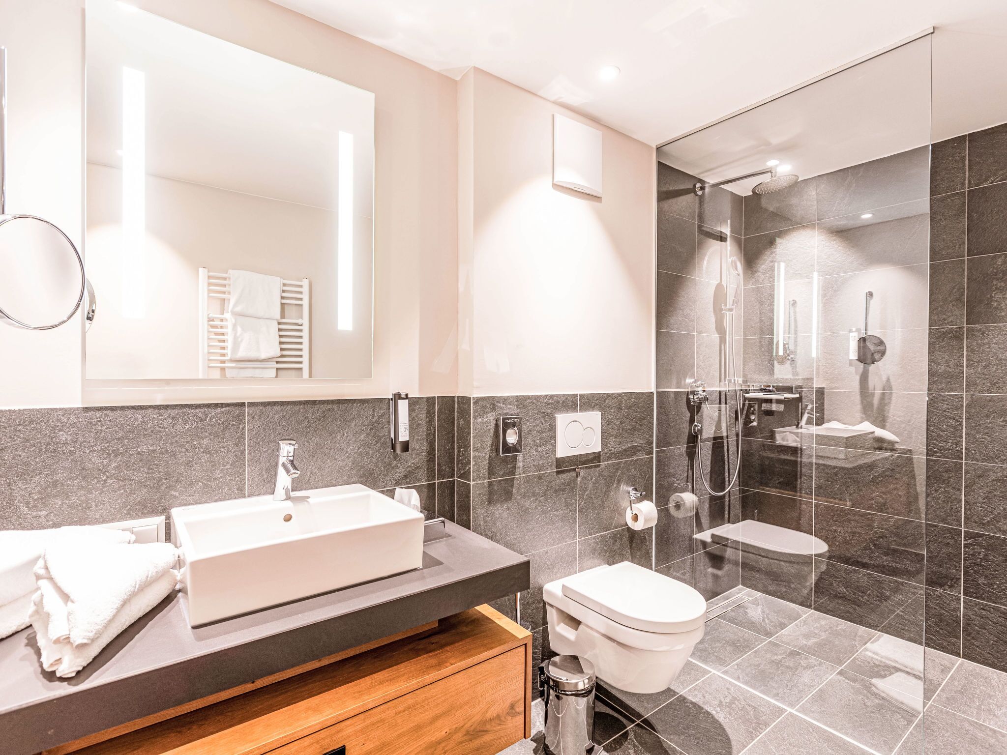 Une salle de bain moderne avec un grand miroir, un lavabo, des toilettes et un espace douche.