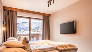A hotel room with a bed, a TV mounted on the wall, and a large window with a mountain view. - Penthouse mit 3 Schlafzimmern by Interhome (Ehrwald)