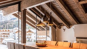 A spacious dining area with a wooden table and leather chairs, large windows offering a view of snow-capped mountains and traditional buildings. - Penthouse mit 3 Schlafzimmern by Interhome (Ehrwald)