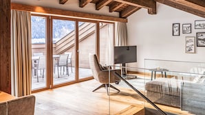 A spacious living room with a large sliding glass door leading to an outdoor area, a modern sofa, a television, and framed pictures on the wall. - Penthouse mit 3 Schlafzimmern by Interhome (Ehrwald)