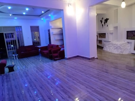 A spacious living area with a wooden floor, red sofas, and a white reception desk.