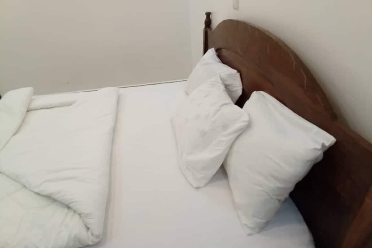 A bed with white bedding and a wooden headboard.