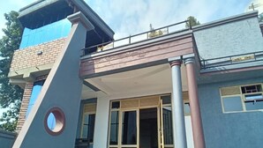 A modern building with a prominent entrance, large windows, and a stone facade. - Queen Greenstars Apartment  (Gisenyi)