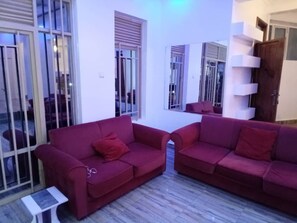Un salon avec deux canapés rouges, une petite table et un escalier avec des rampes blanches.