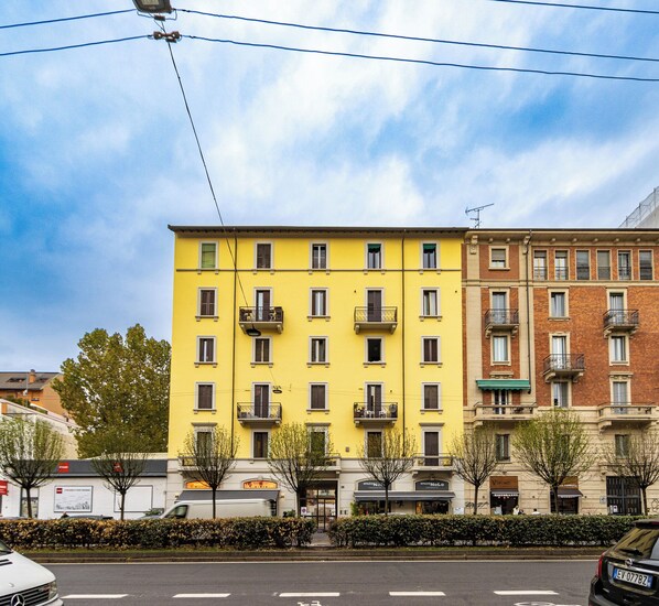 Um edifício amarelo com várias varandas e um prédio de tijolos ao lado.