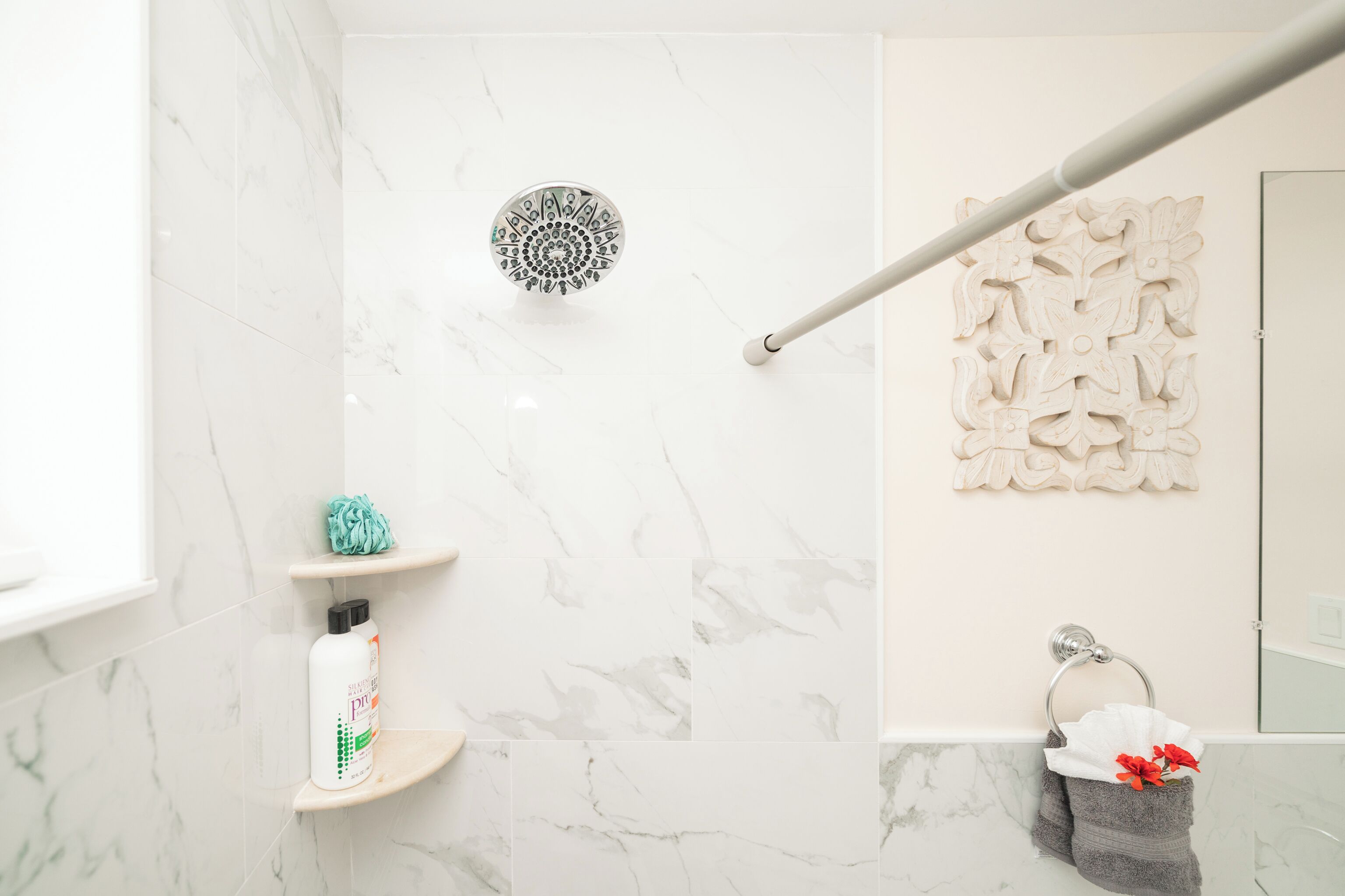 Une salle de bain avec une douche, des murs en marbre, un porte-serviettes et un élément décoratif mural.