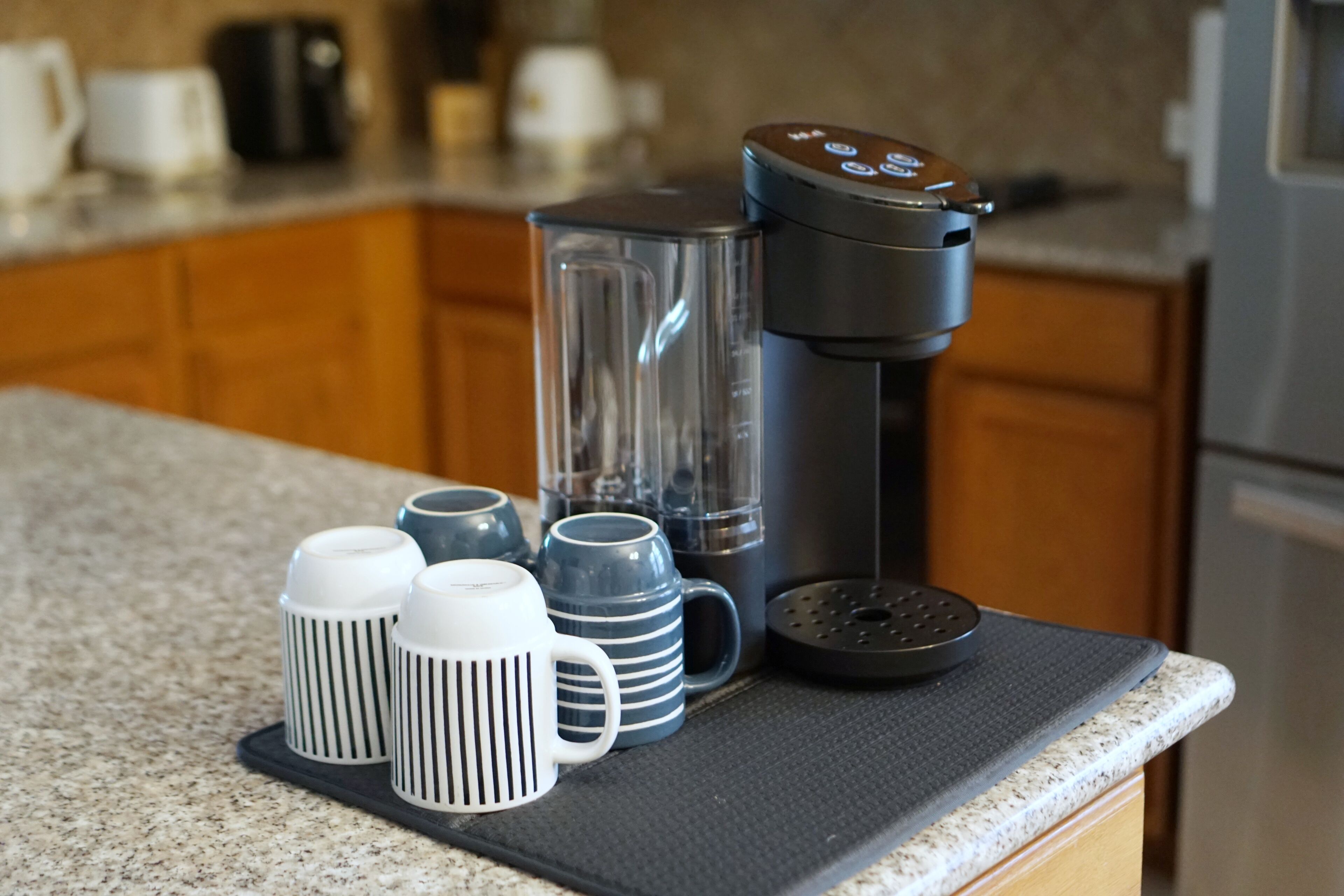 A kitchen counter with a coffee maker, a blender, and several mugs.