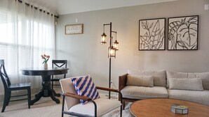 Un salon comprenant une table basse ronde, un canapé, une table à manger avec des chaises et un lampadaire.