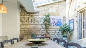 A dining area with a long wooden table, chairs, and potted plants.