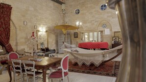 A room with a wooden dining table, white chairs, a red sofa, and a hammock.