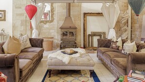 A cozy living room with a stone wall, a wood-burning stove, and two brown leather sofas.