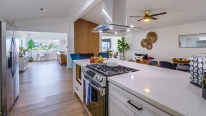 Une cuisine moderne dotée d’un îlot central, d’un four encastré et d’un ventilateur de plafond.